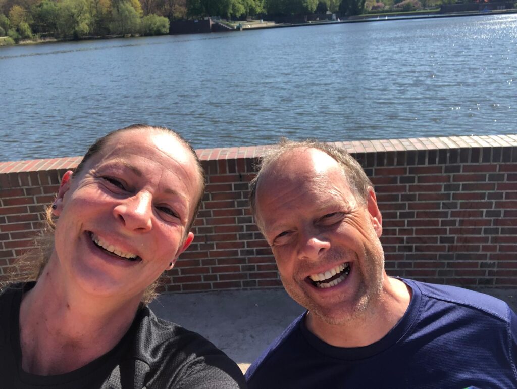 Auf dem Bild sieht man Trainerin Mandy und Ralf Boie lachend bei sonnigem Wetter am Wasser in Hamburg. Mandy leitet den Montag-Laufkurs bei Lunge als Vertretung für Boie-Sports – professionelles Lauftraining mit Fokus auf Lauftechnik, Freude am Laufen und individueller Betreuung.