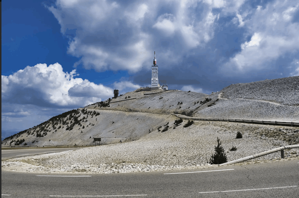 Auf dem Bild sieht man den Mont Ventoux in Frankreich mit seiner kargen, steinigen Landschaft, der markanten weißen Wetterstation mit rotem Antennenmast und der kurvigen Straße zum Gipfel. Im Juni 2026 fahren fünf Athleten von Boie-Sports diesen legendären Berg im Rahmen eines Radsportevents hoch – ein Symbol für Ausdauer, Willenskraft und gemeinsames Radtraining.